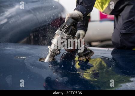 Coltivare l'uomo in uniforme alimentando l'aereo moderno mentre si lavora campo aereo Foto Stock