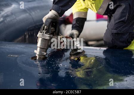 Coltivare l'uomo in uniforme alimentando l'aereo moderno mentre si lavora campo aereo Foto Stock