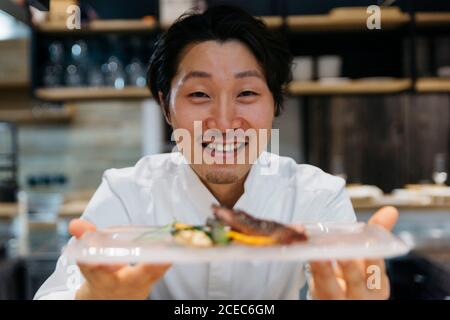 Chef cucina in ristorante insegna il piatto di cibo Foto Stock