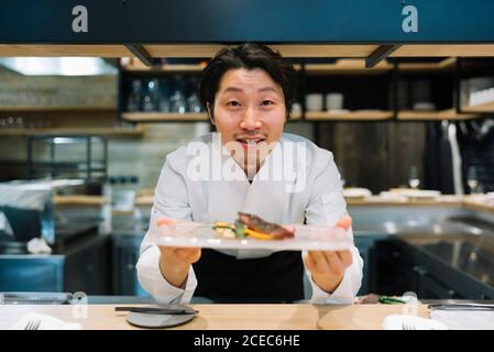 Chef cucina in ristorante insegna il piatto di cibo Foto Stock
