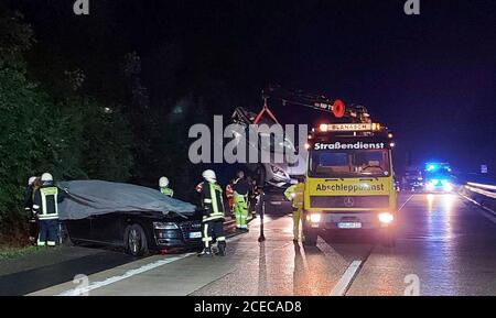 31 agosto 2020, Baden-Wuerttemberg, Boxberg: Un veicolo di scorta del primo ministro Kretschmann è in piedi sulla strada dopo un incidente, mentre un'altra auto coinvolta nell'incidente è sollevata su un camion di traino. Kretschmann sopravvisse all'incidente stradale senza danni. Secondo un portavoce del governo, il capo della macchina del governo aveva slittato il lunedì sera su Autobahn 81 su una strada bagnata, ha urtato con la barriera d'urto e poi è venuto ad un arresto nella spalla dura. Tuttavia, due occupanti di un'altra vettura sono stati gravemente feriti. La loro auto aveva subito slittato poco dopo nello stesso punto tra Möck Foto Stock