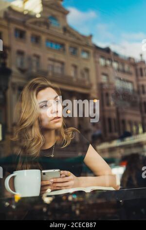 Donna che utilizza lo smartphone nel cafe Foto Stock