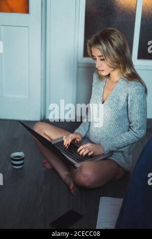 Donna seduta sul pavimento che lavora con un computer portatile Foto Stock