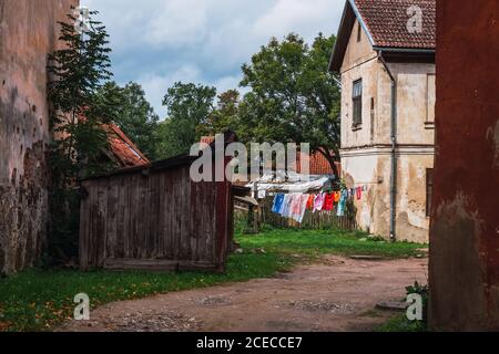 Splendida vista su abiti colorati appesi sulla corda nel cortile tra le case shabby in piccolo insediamento Foto Stock