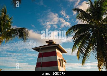 Spiaggia tropicale con piccolo faro di legno sul molo con case gialle in fila, Panama Foto Stock