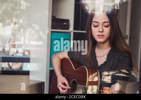 Donna che suona la chitarra alla finestra Foto Stock