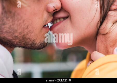 Primo piano di un giovane e una donna irriconoscibili che si baciano mentre si sono in piedi per strada Foto Stock