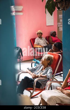 LA HABANA, CUBA - NOVEMBRE, 6 , 2018: Vista laterale anziani afro-americani seduti sui posti a sedere in camera con ventilatore a Cuba Foto Stock
