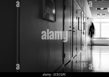 Una persona irriconoscibile in movimento si oscura in un corridoio ospedaliero abbandonato Foto Stock