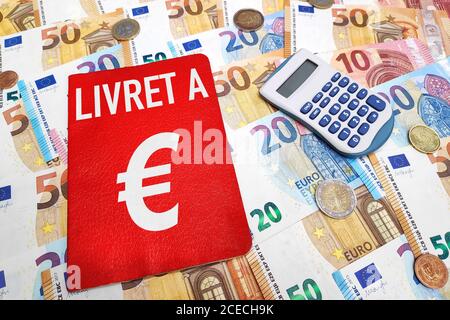 Livret A e una calcolatrice sulla parte superiore di una pila di banconote e monete in euro. Il Livret A è un prodotto finanziario storico offerto dalle banche francesi. Foto Stock