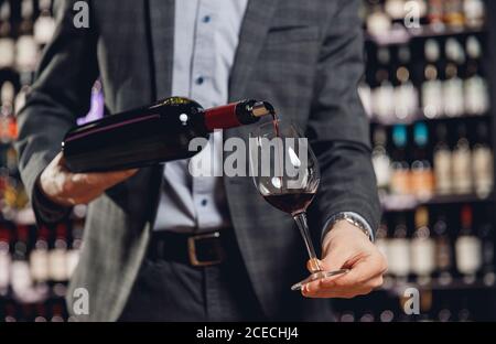 Sommelier che versa vino rosso in bicchieri a gambo lungo Foto Stock
