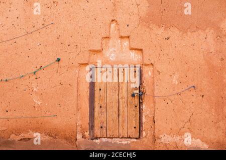 Finestra chiusa in legno in casa tradizionale marocchina con parete di colore rosso terracotta. Texture shabby, sfondo. Stile arabo in architettura. Foto Stock