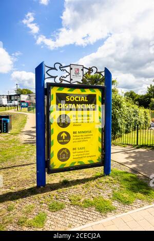 Accedi a Woking Park, Woking, Surrey, ricordando alle persone di rispettare le regole di allontanamento sociale durante il conronavirus Covid-19 pandemia: La nuova normalità Foto Stock