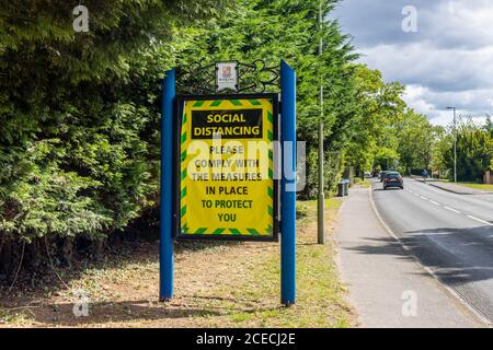 La nuova normalità: Grande cartello stradale, Woking, Surrey, che ricorda alle persone di rispettare le regole di allontanamento sociale durante la pandemia del conronavirus Covid-19 Foto Stock