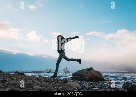 Felice ragazza equilibrando su roccia in mare Foto Stock