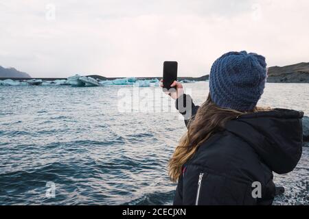 Donna che scatta foto sulla spiaggia fredda Foto Stock