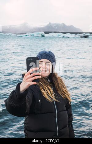 Donna che scatta foto sulla spiaggia fredda Foto Stock