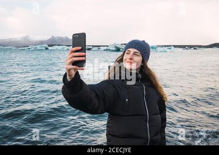 Donna che scatta foto sulla spiaggia fredda Foto Stock