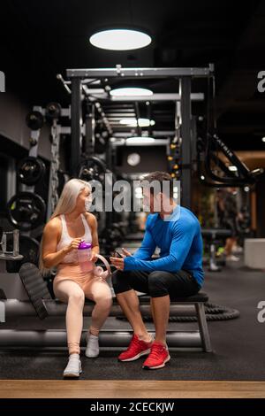 Uomo e donna seduti in palestra e ridendo Foto Stock