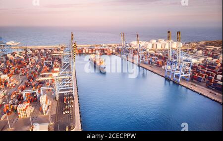 Nave container che lascia il porto, esportazione e importazione di attività e logistica. Vista dall'alto del tramonto Foto Stock