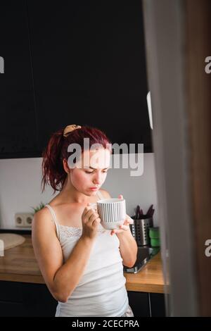 Donna di bere il caffè in cucina Foto Stock