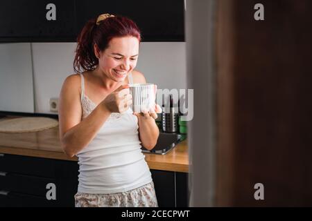 Donna di bere il caffè in cucina Foto Stock