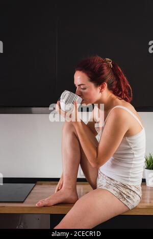 Donna di bere il caffè in cucina Foto Stock