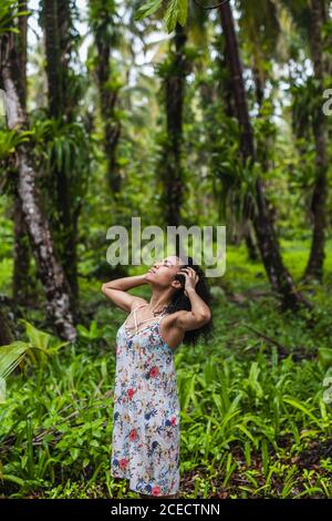 Attraente donna ispanica con testa e mani su capelli in verde foresta nelle Isole Bocas del Toro, Panama Foto Stock