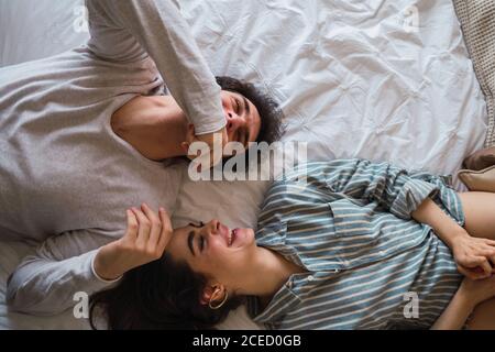 Uomo e donna allegri sdraiati a letto Foto Stock