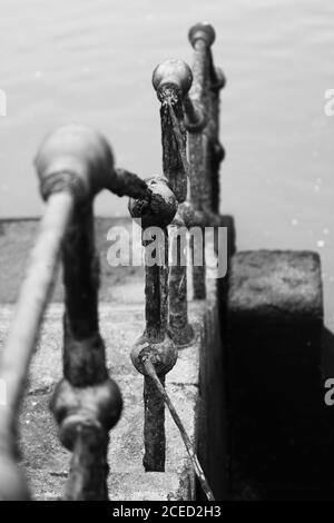 Immagine in scala di grigi di una ringhiera metallica sul fiume Foto Stock