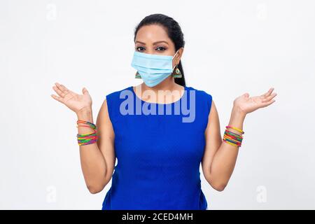Bella donna indiana indossare maschera di protezione Covid-19. Donna con braccia aperte in posizione rilassata. Foto Stock