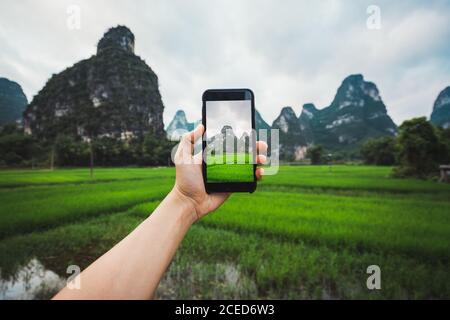 Crop mano scattando foto in risaie di Guangxi cinese Foto Stock