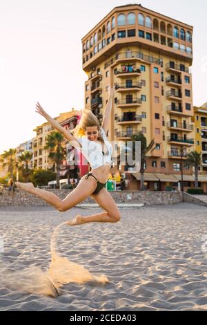 Donna flessibile in piedi su una gamba sulla spiaggia Foto Stock