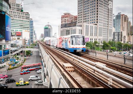 Fotografando il treno sopraelevato che si arriva alla stazione dello skytrain Asoke BTS sopra l'Asok e Sukhumvit Rd, allo svincolo di Bangkok, Thailandia. Foto Stock