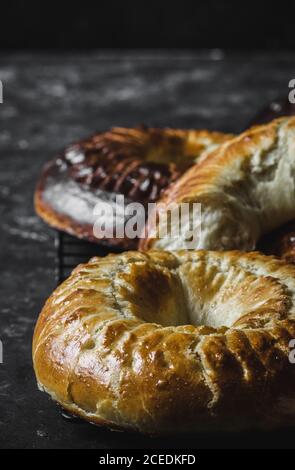 Primo piano di deliziose corone brioche fresche giacenti su marmo piano portapaziente in camera oscura Foto Stock