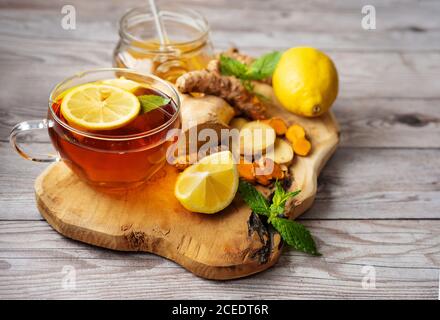 Tazza di tè curcuma allo zenzero su tavola di legno con ingredienti Foto Stock