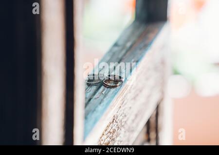 Vista in primo piano di due anelli dorati di nozze messi su legno ripiano vicino allo specchio Foto Stock