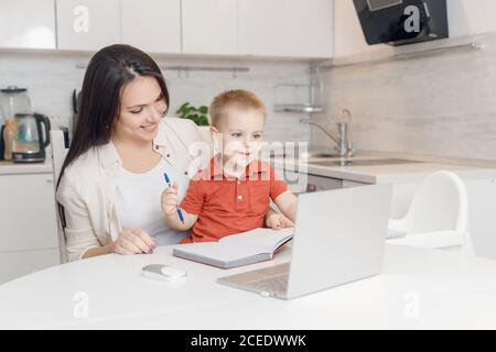 Madre e figlio stanno imparando a scrivere. Donna insegna bambino alfabeto studio online Foto Stock