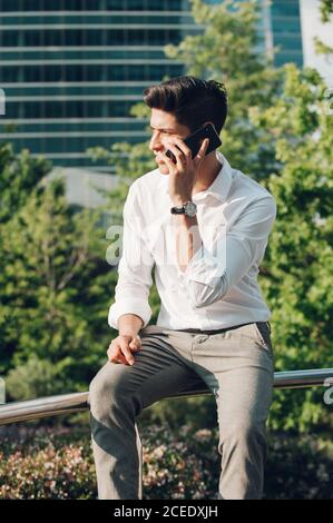 Giovane uomo che parla telefono sulla ringhiera Foto Stock