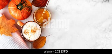 Vista dall'alto del latte di spezie di zucca o del caffè con schiuma cremosa, piccola zucca arancione, maglione bianco su sfondo bianco Foto Stock