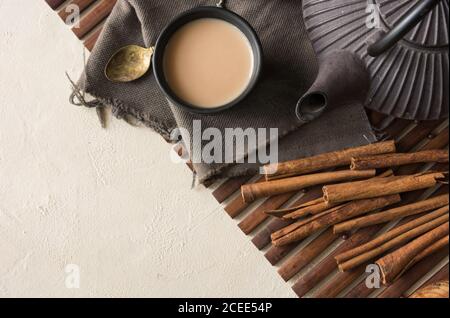 Tazza orientale di tè Chai, i suoi ingredienti con latte, cannella, zenzero, pepe bianco e cardamomo Foto Stock