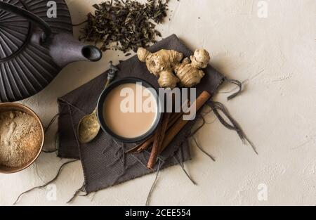 Tazza orientale di tè Chai, i suoi ingredienti con latte, cannella, zenzero, pepe bianco e cardamomo Foto Stock