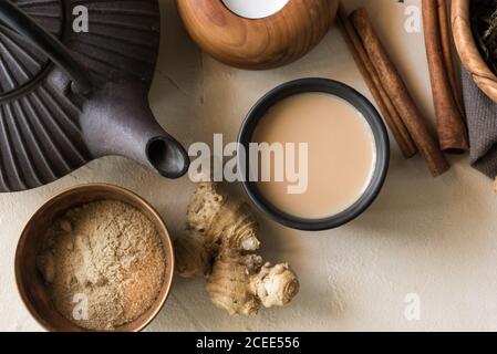 Tazza orientale di tè Chai, i suoi ingredienti con latte, cannella, zenzero, pepe bianco e cardamomo Foto Stock