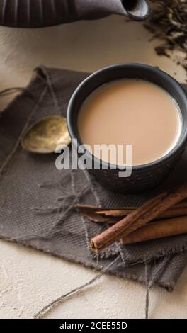 Tazza orientale di tè Chai, i suoi ingredienti con latte, cannella, zenzero, pepe bianco e cardamomo Foto Stock