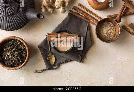 Tazza orientale di tè Chai, i suoi ingredienti con latte, cannella, zenzero, pepe bianco e cardamomo Foto Stock