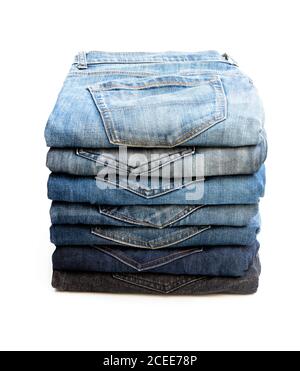 Lotto di jeans usati accatastati in un palo isolato sopra bianco Foto Stock