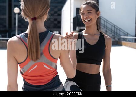 Due donne allegre in forma fisica indossare dando alto cinque mentre correre in città Foto Stock