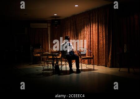 uomo in tuta seduto su sedia in bella sala e tenendo il disco in scatola. Foto Stock