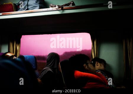 Vista laterale delle persone che dormono in autobus o in treno con i bagagli sul ripiano superiore. Foto Stock