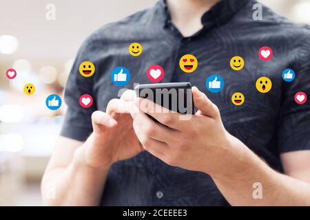 Uomo che usa lo smartphone mobile, primo piano. Immagine di un giovane uomo che usa uno smartphone mobile e sorridente. Foto Stock